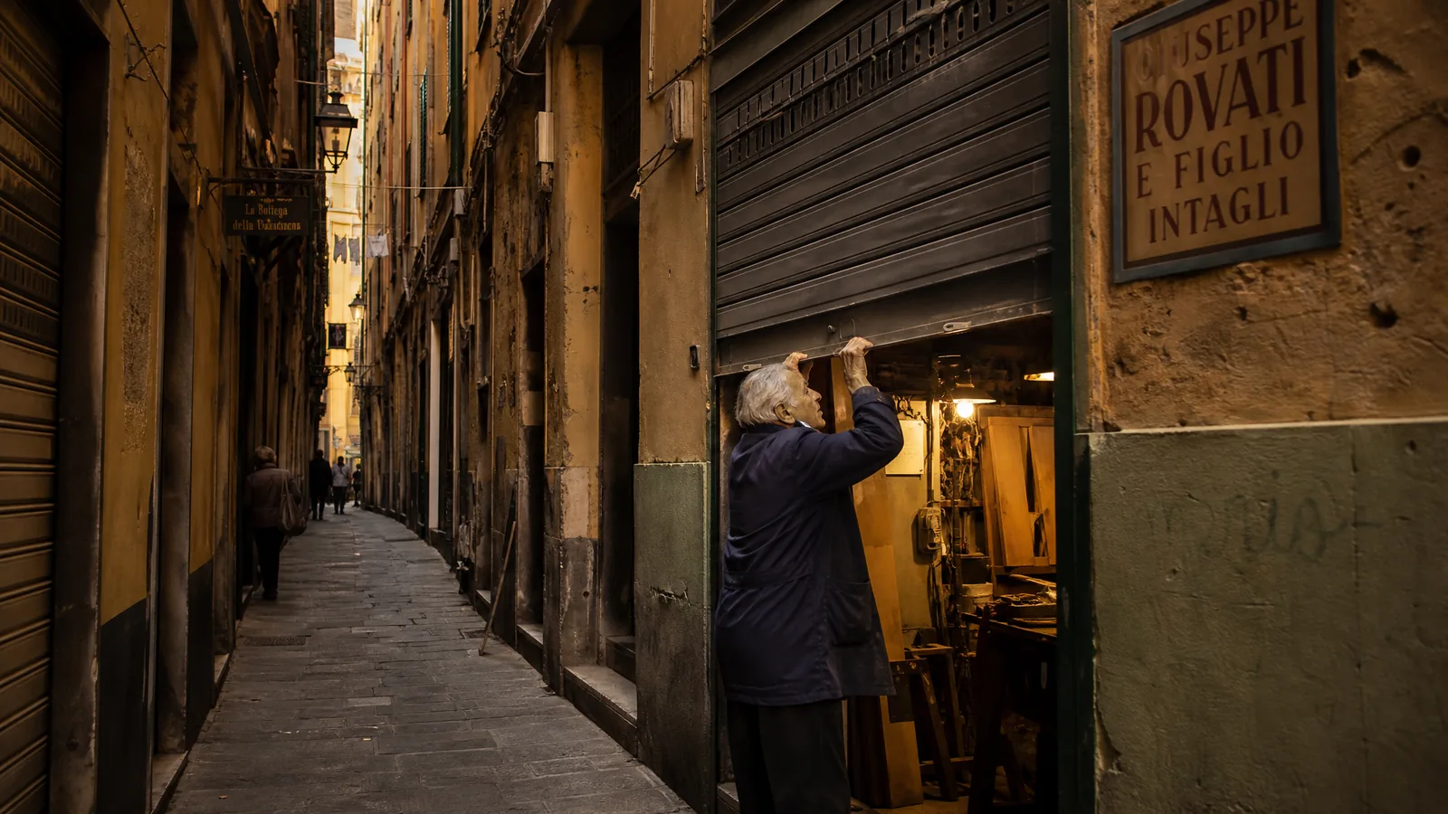 Caruggio genovese, artigiano che apre la serranda