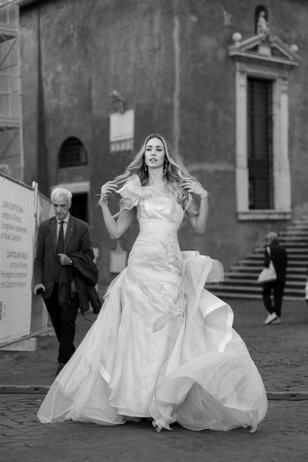 Il motivo dipinto a mano che si apre sulla gonna dell'abito in movimento, per le strade di Roma