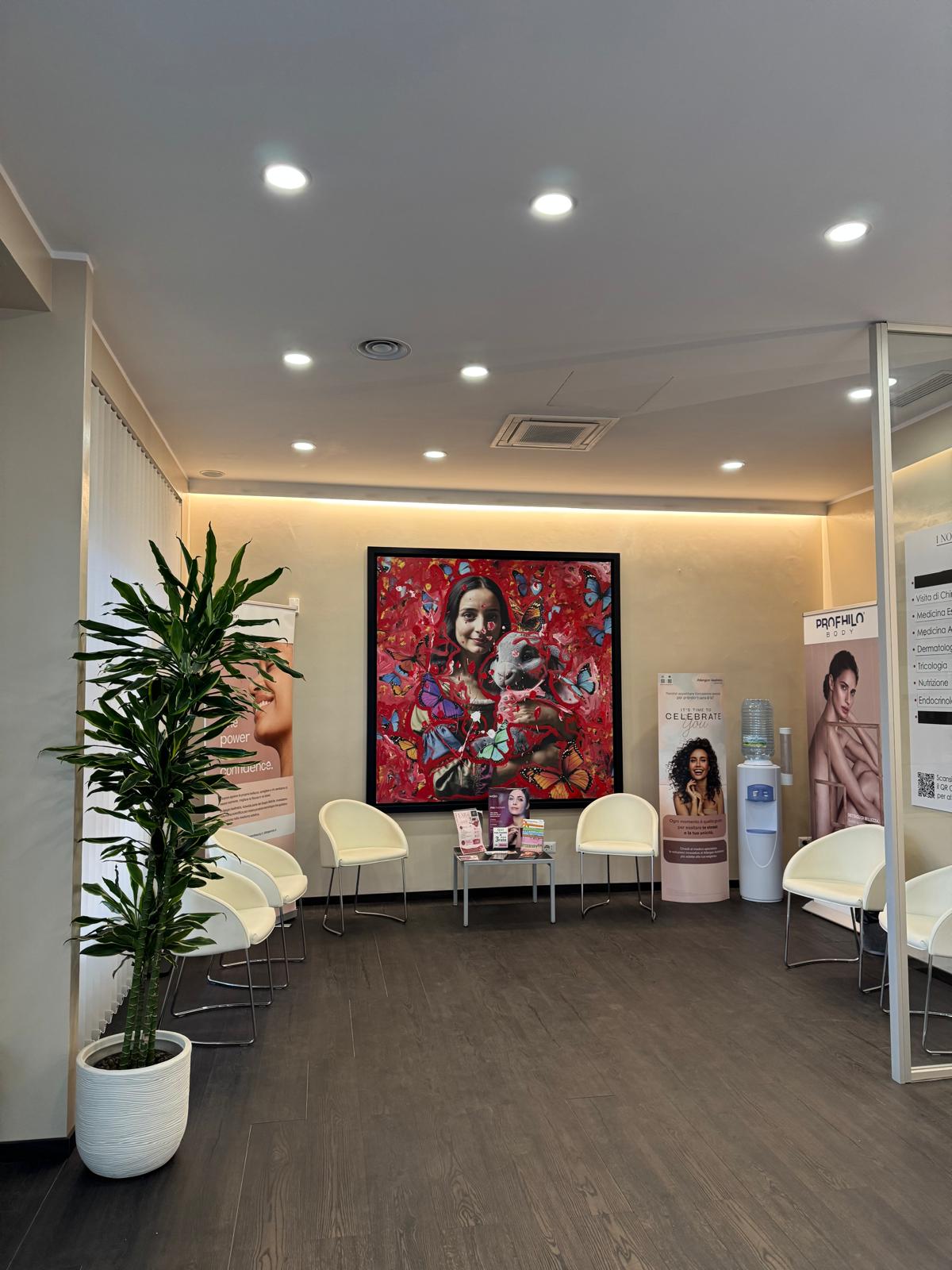 La sala d'attesa con poltroncine bianche e un grande quadro rosso